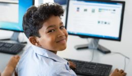 Young boy smiling while working at a computer