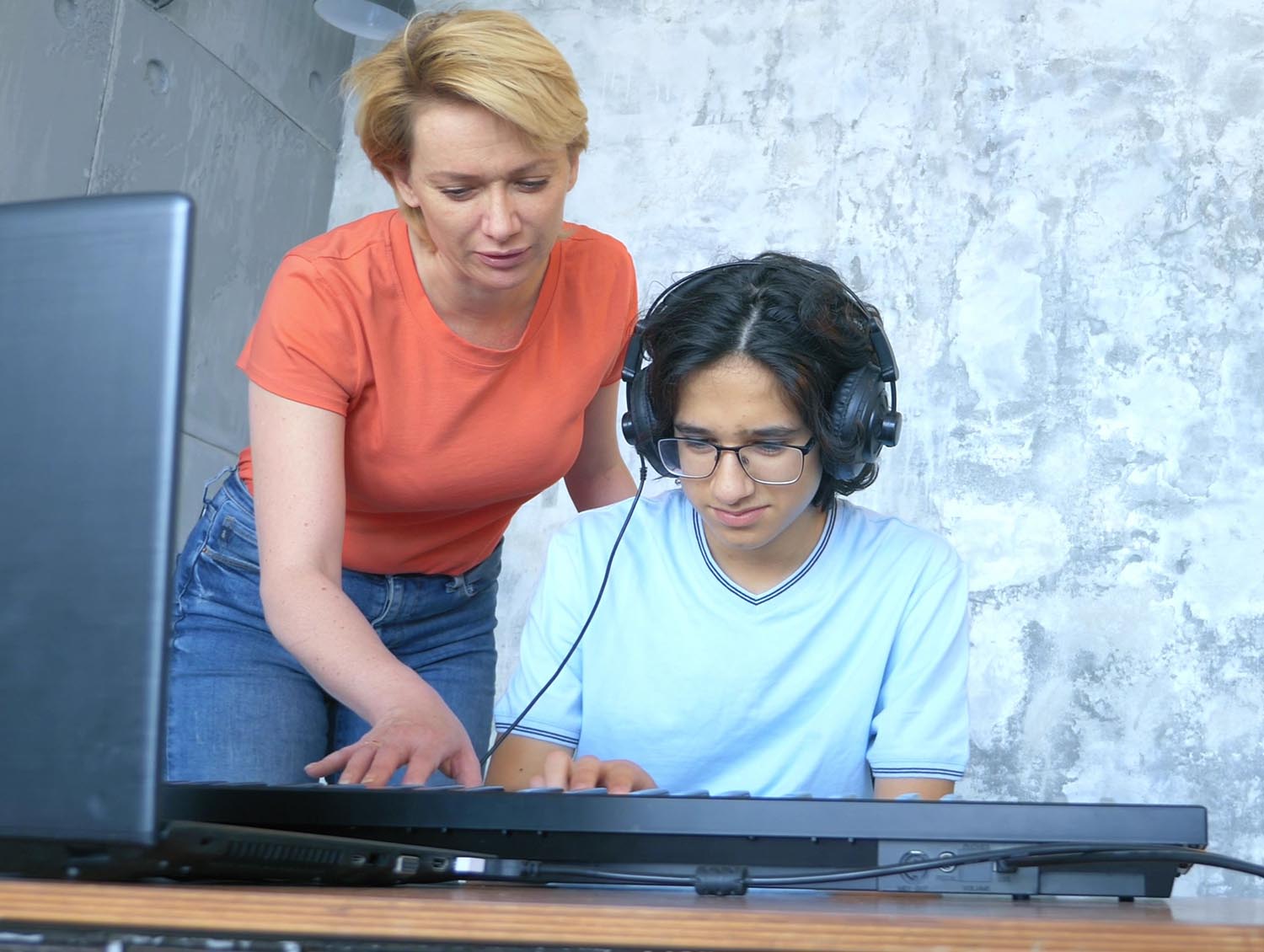 Teacher and student with headphones composing music